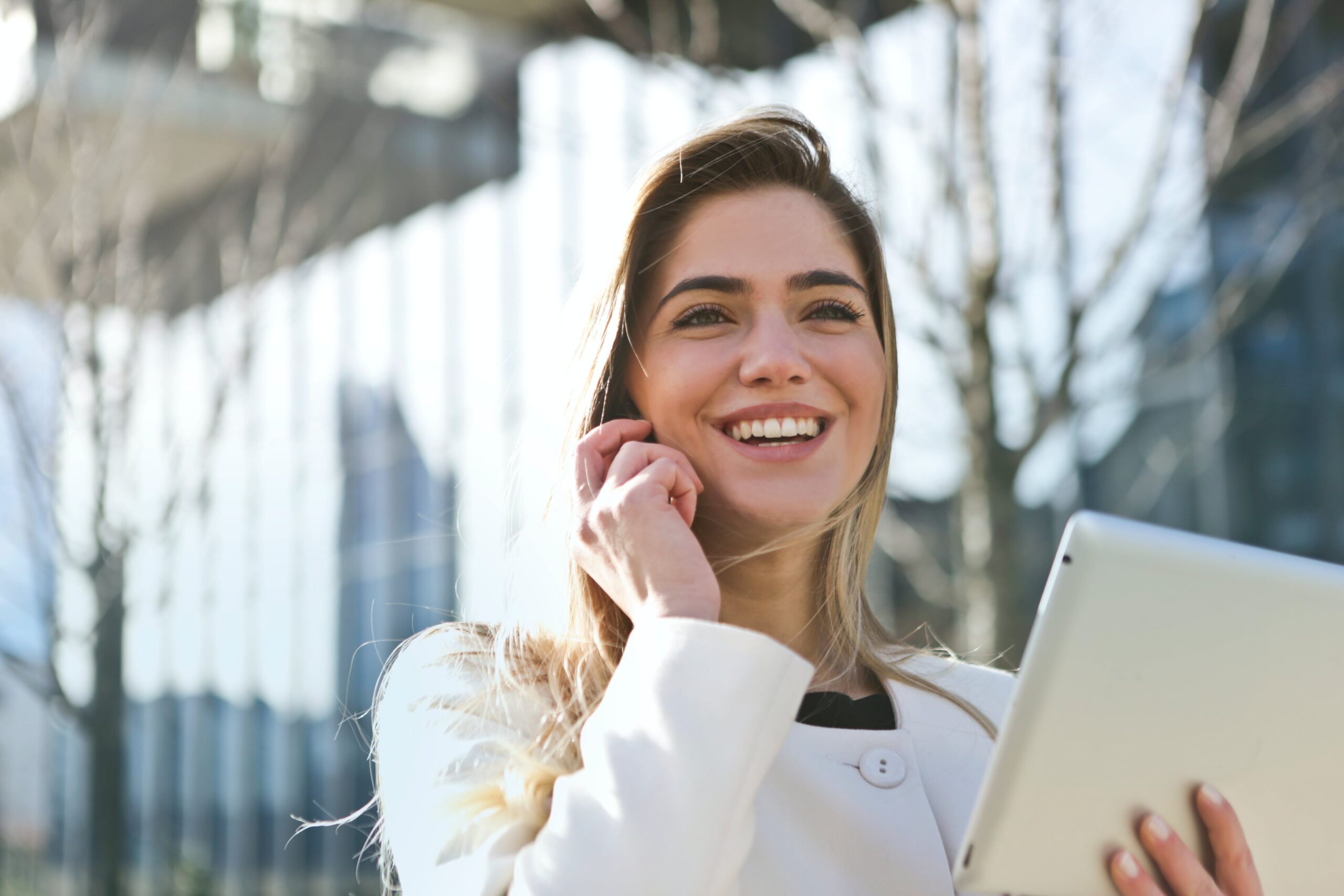 Foto einer fröhlichen Business Frau beim Telefonieren mit einem Laptop in der Hand