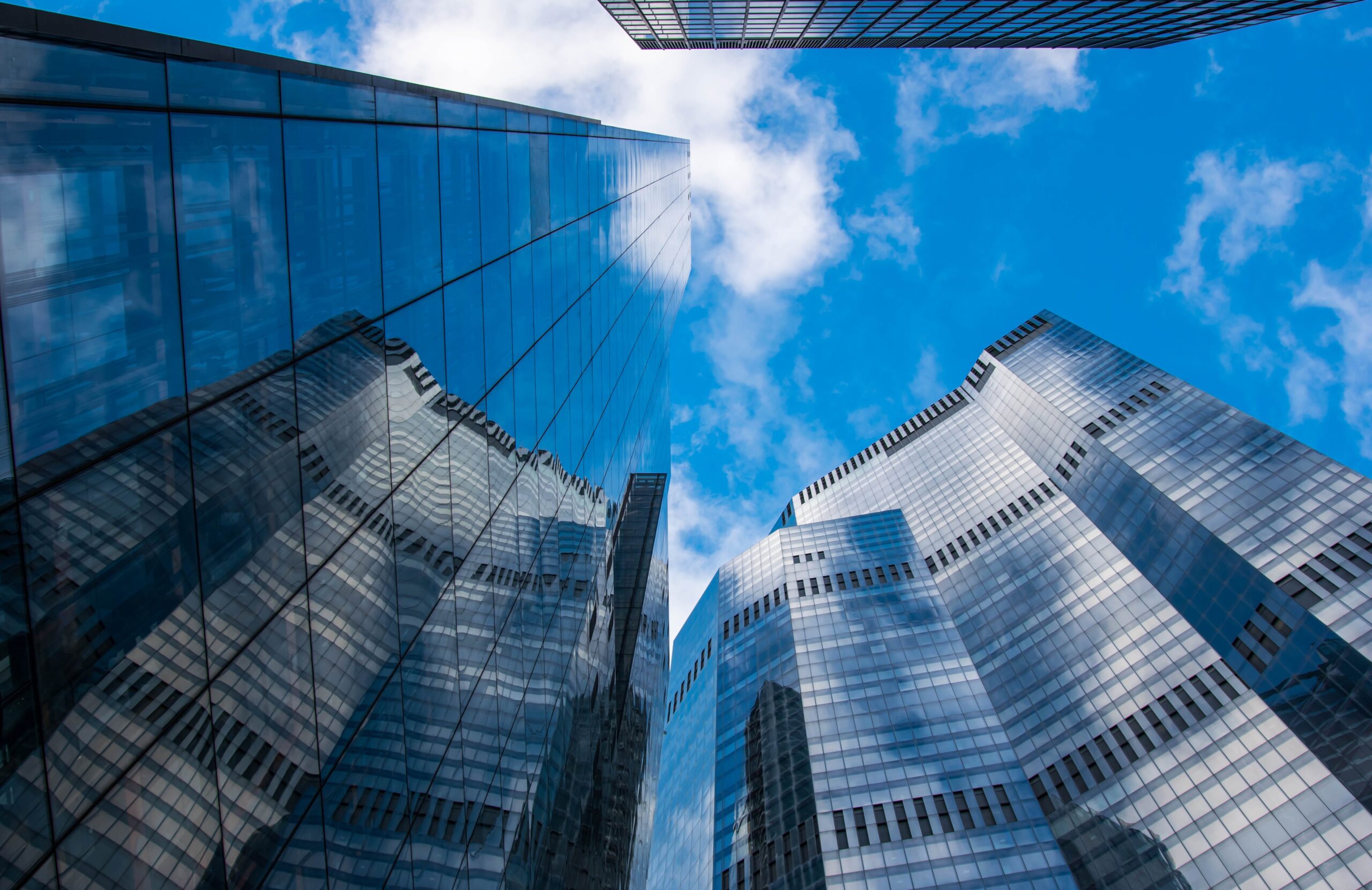 Foto eines Central Business Districts mit gläsernen Wolkenkratzern, es wurde zwischen den Türmen senkrecht Richtung Himmel fotografiert.